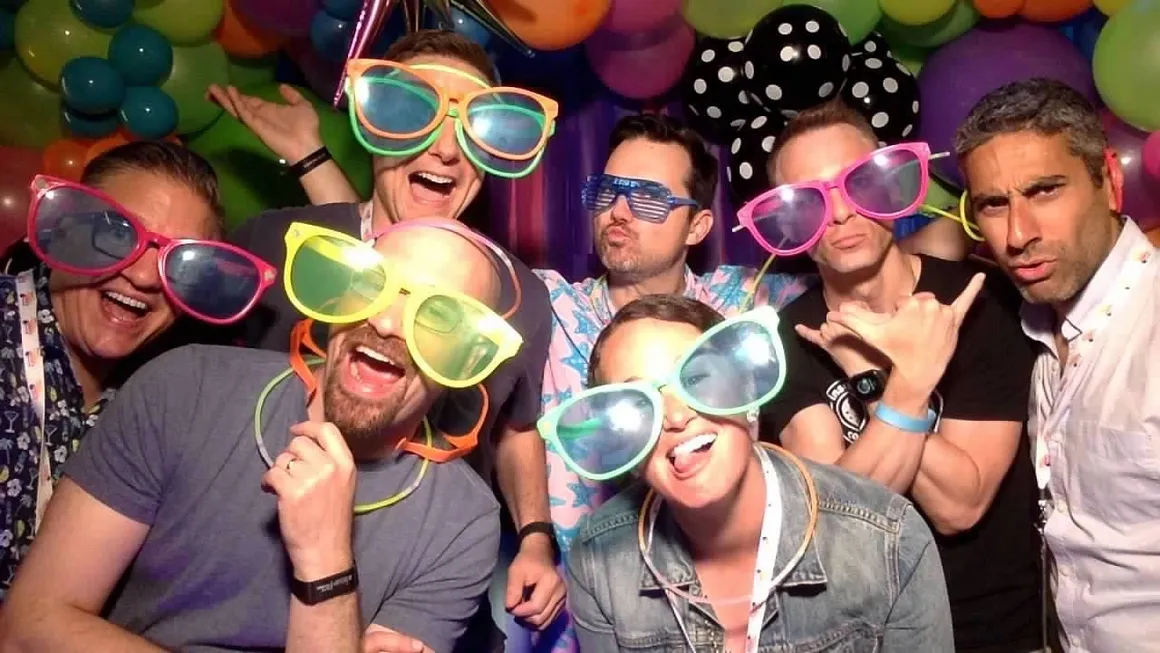 Group photo booth moment with oversized neon glasses