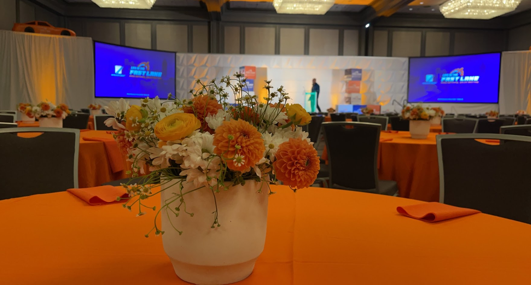 Orange floral centerpiece and stage setup for a corporate event